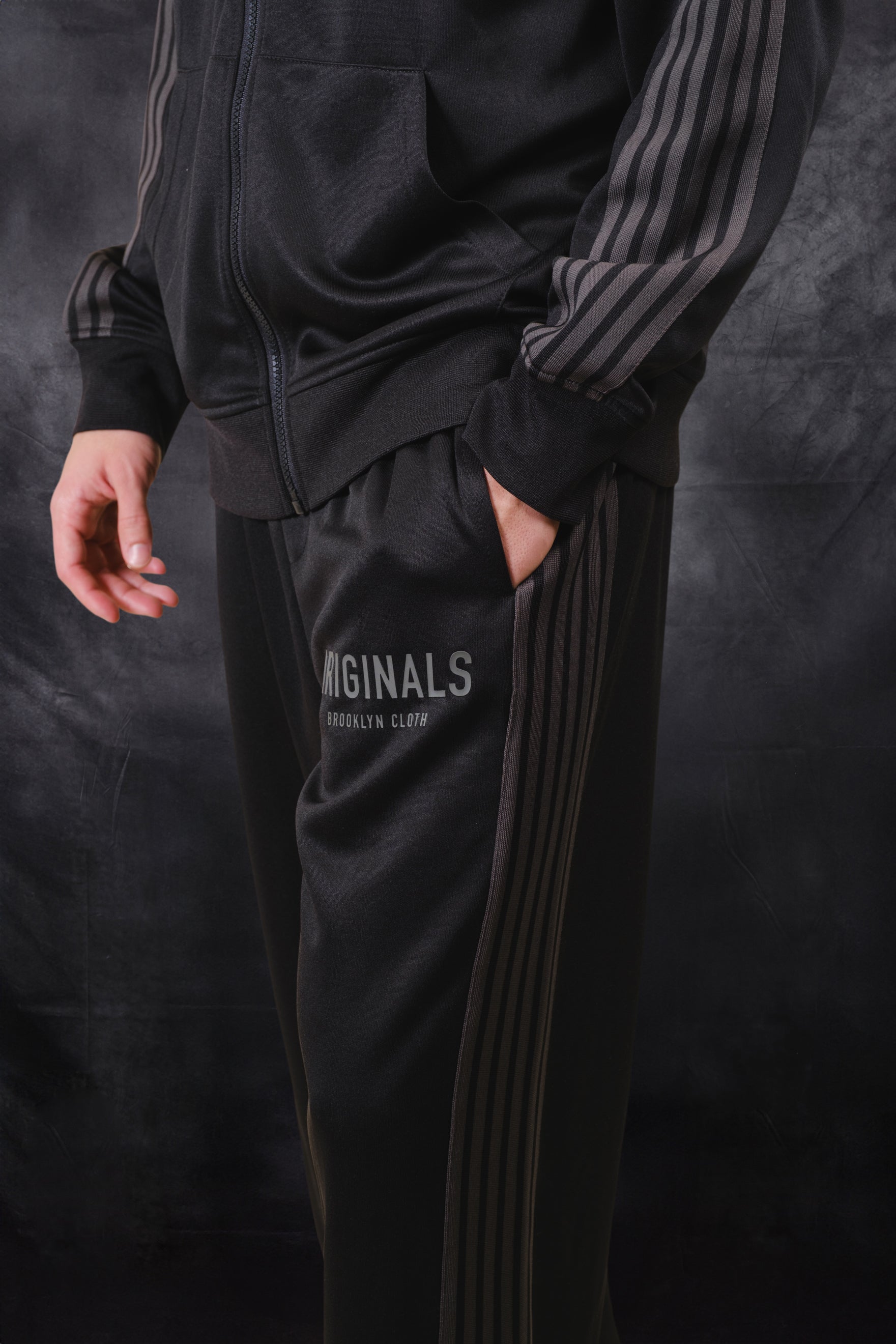 Men's loose fit pique track pant with side strip panels and Originals logo on upper left thigh 
#color_black