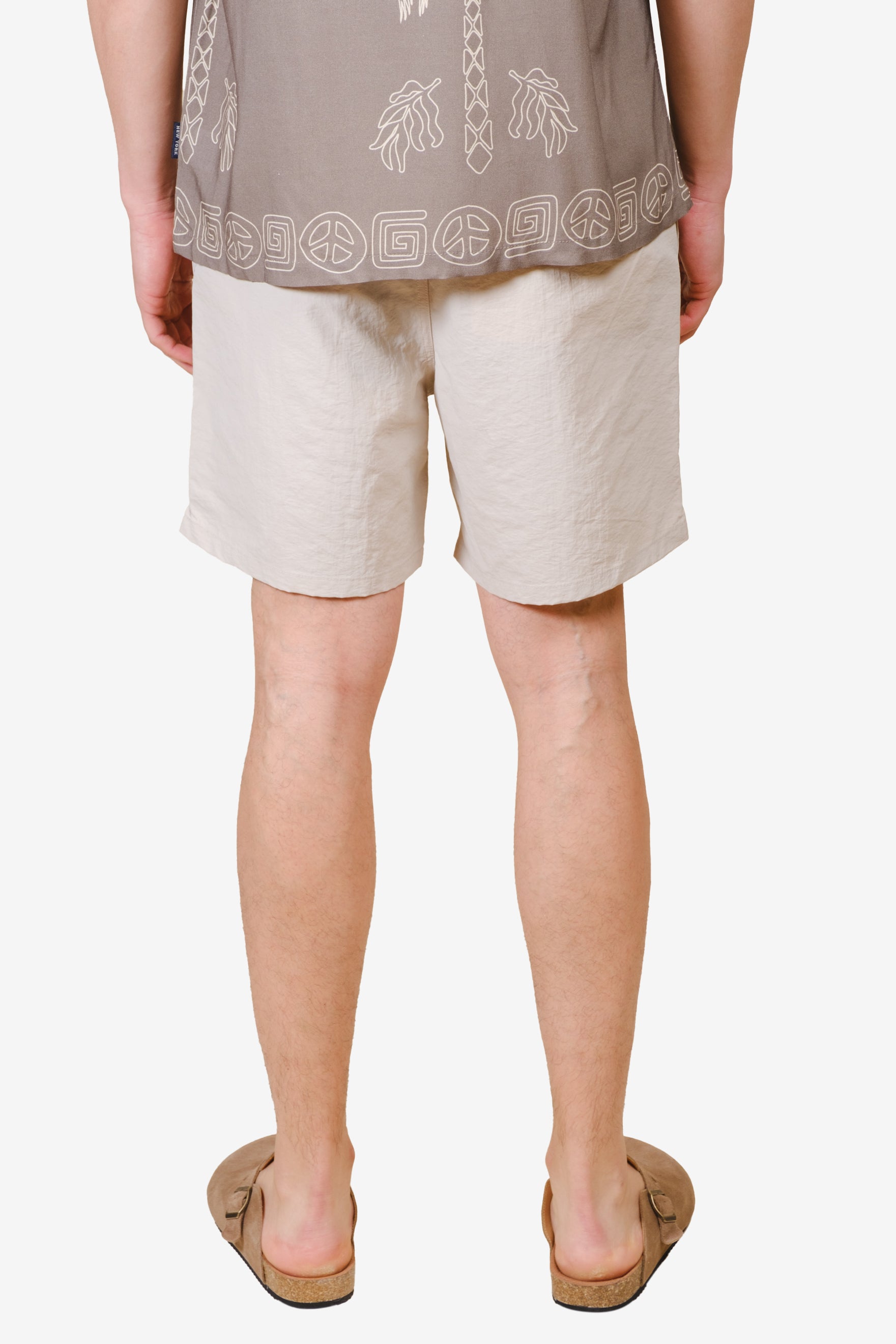 Lightweight monotone crinkle nylon shorts with an elastic waistband and flower detail on bottom right corner 
#color_sand